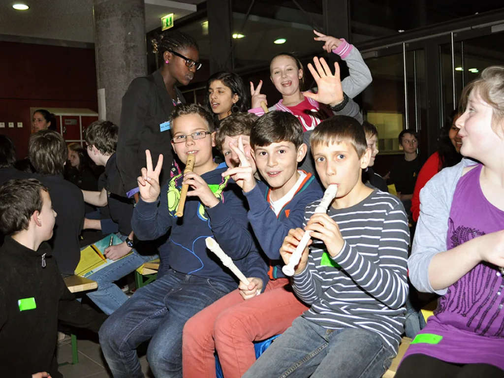 Kinder sitzen mit Blockflöten im Publikum.